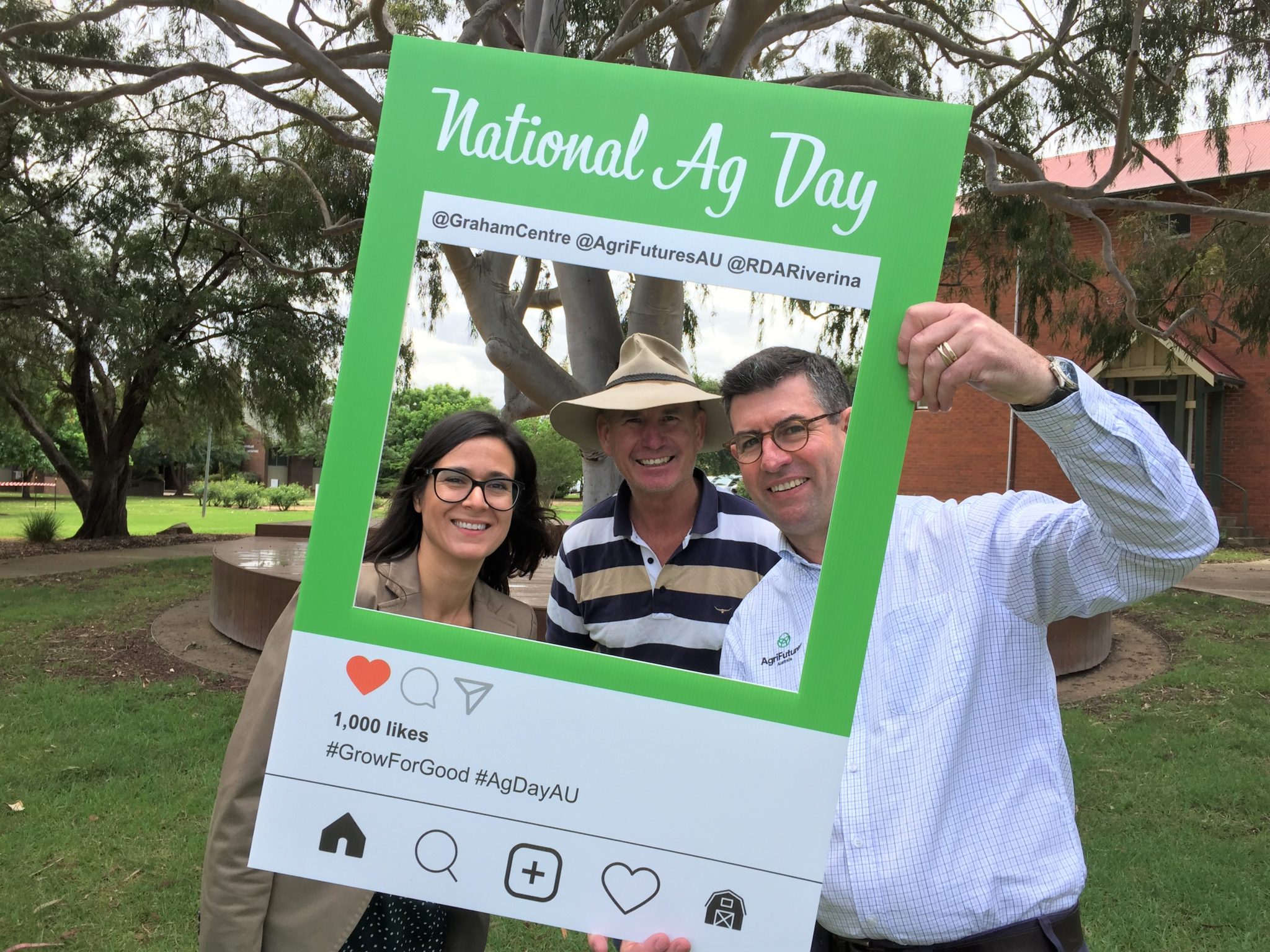 Three people standing in front of a National Agriculture Day frame