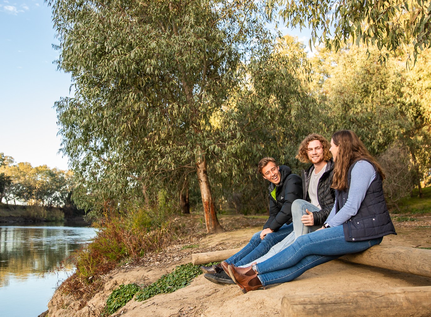 AgriFutures Horizon Scholars Aaron James, Ashley Smith and Jessica Zieltjes sitting on the bank of a river