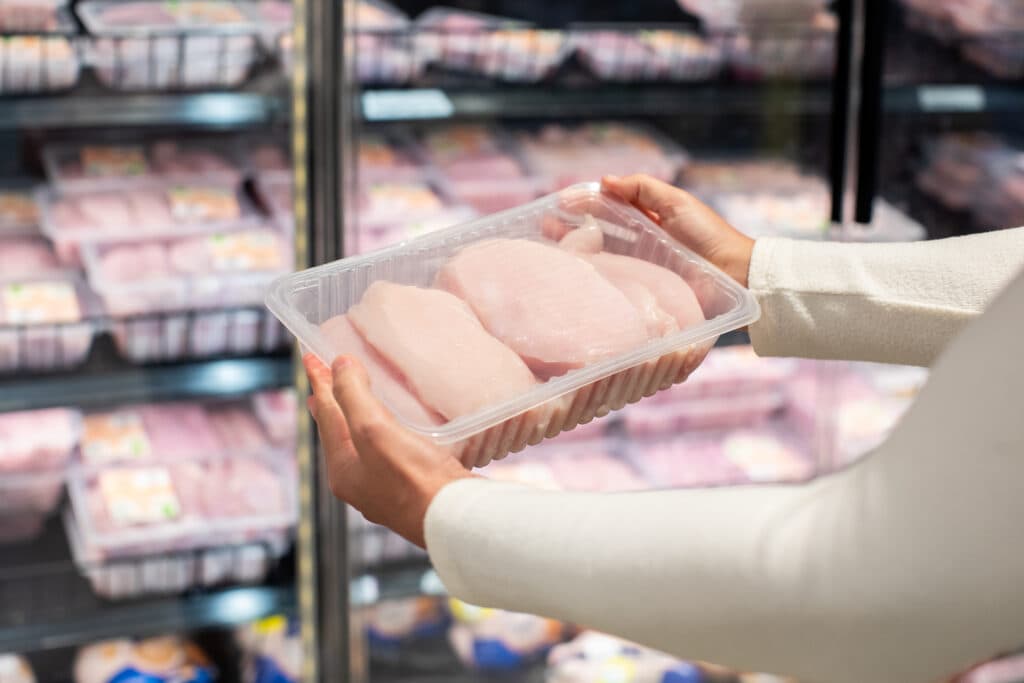 consumer holding chicken in supermarket