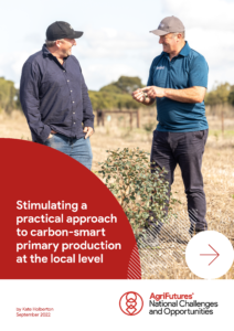 Two men in casual clothes and caps talk in a dry, grassy field beside a shrub, illustrating rural agriculture for the AgriFutures report "Stimulating a practical approach to carbon-smart primary production at the local level.