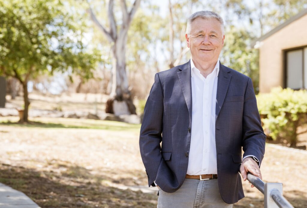 Mick Veitch, AgriFutures Australia Chair. Mick has grey hair and is wearing a navy blazer over a white shirt with tan trousers.