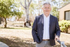 Mick Veitch, AgriFutures Australia Chair. Mick has grey hair and is wearing a navy blazer over a white shirt with tan trousers.