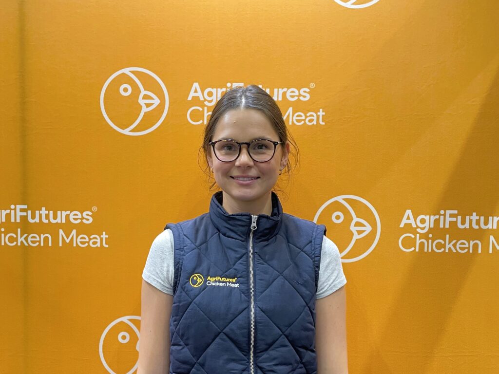 Amelia Sofra named 2026 Gary Sansom Scholar, stands in front of an orange AgriFutures Chicken Meat backdrop