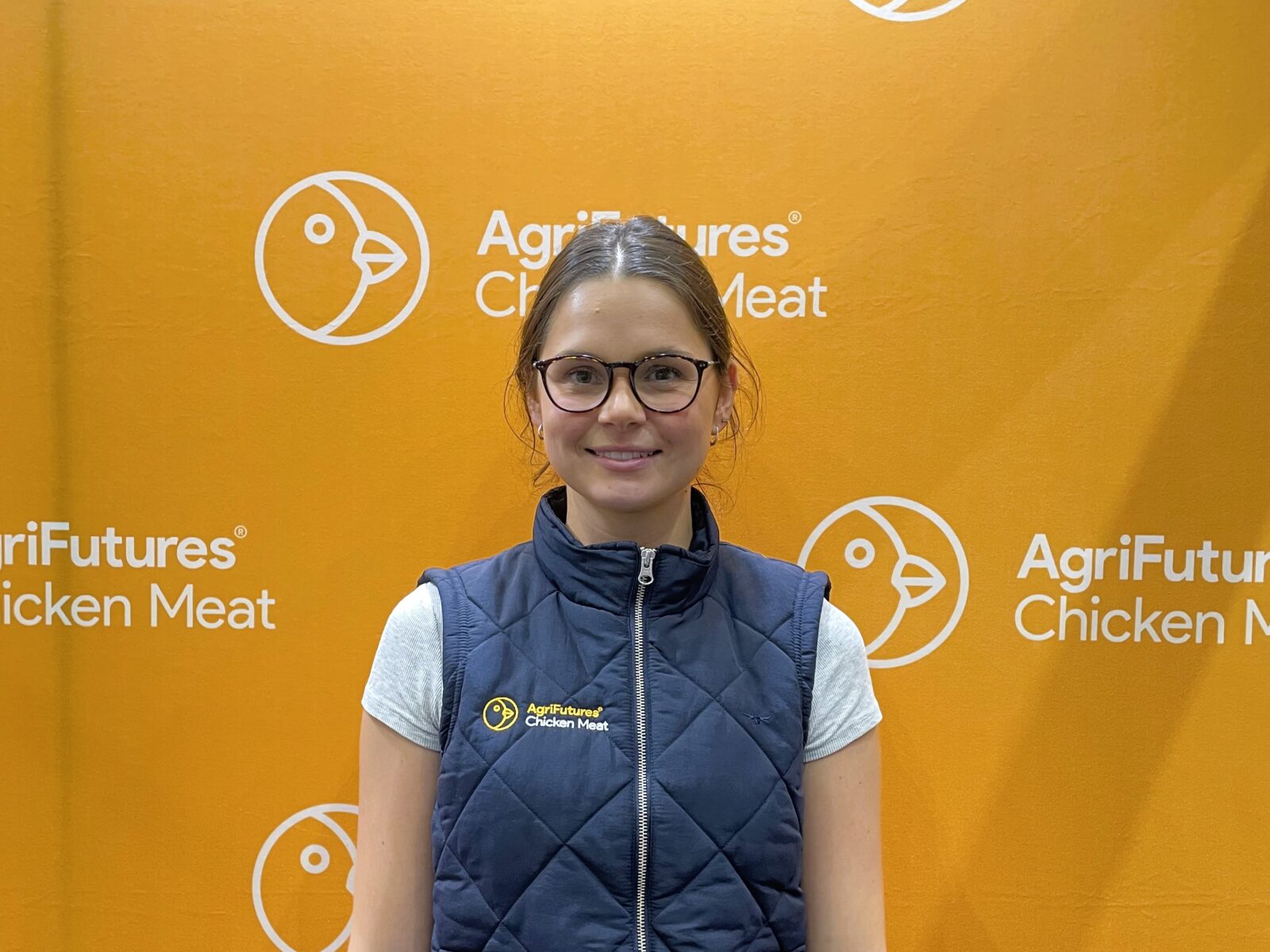 Amelia Sofra named 2026 Gary Sansom Scholar, stands in front of an orange AgriFutures Chicken Meat backdrop